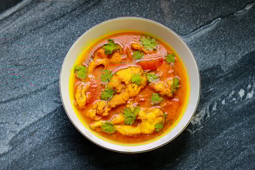 Fish curry in a bowl on a black table. Top view, flat lay photo