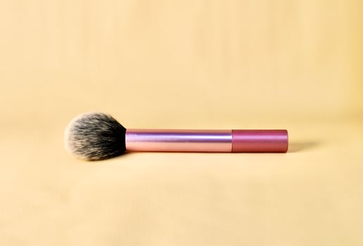 Blush make up brush with pink handle isolated on horizontal brown cream colored background. photo
