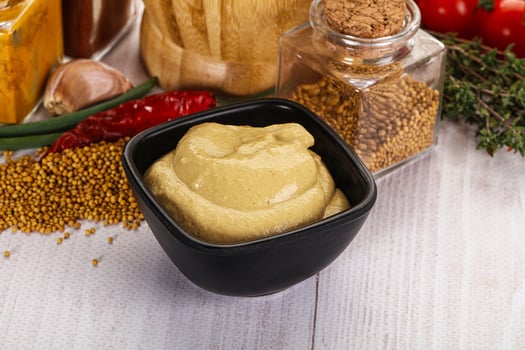A bowl of mustard and other ingredients on a table photo