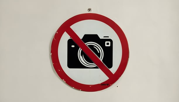 A no camera sign on a white wall photo