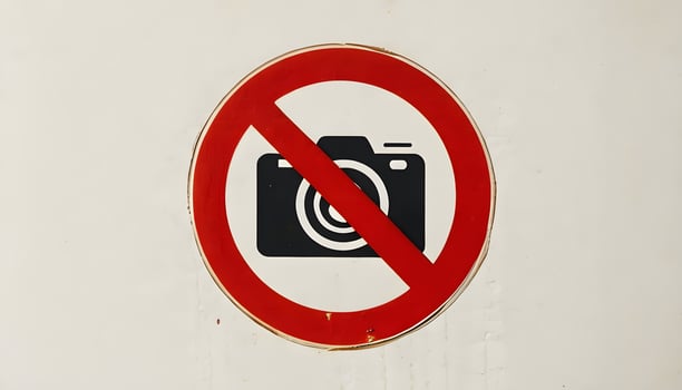 A no camera sign on a white wall photo