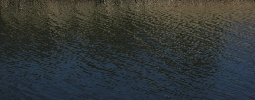Gently rippled river with blue, green and yellow reflections. photo