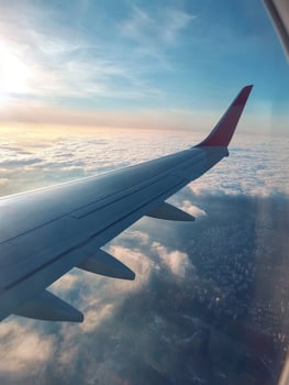 This stunning view showcases a morning flight with a planes wing above fluffy clouds, illuminated by vivid sunlight that brightens the sky and the city below, creating an enchanting atmosphere photo