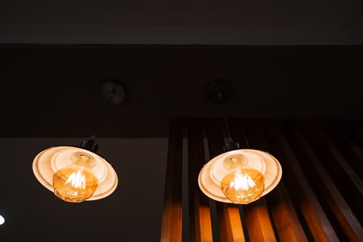 In a cozy, dimly lit room, two inviting bulbs hang from the ceiling, casting a soothing glow that dispels darkness and creates a serene atmosphere for relaxation and enjoyment photo