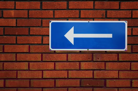 Arrow sign on a red brick wall. photo