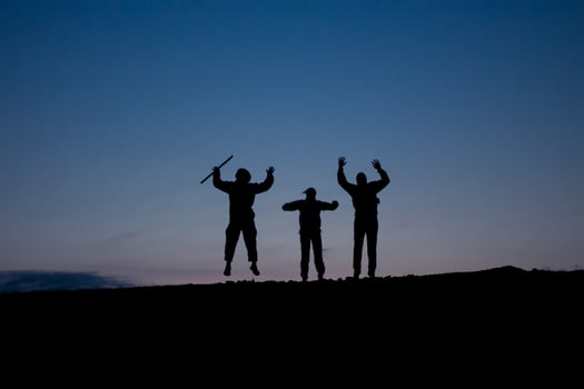 Three people are standing on a hill with their hands up photo