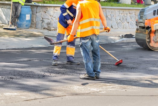 Road workers clean the asphalt pavement on the roadway with a brush and shovel. photo
