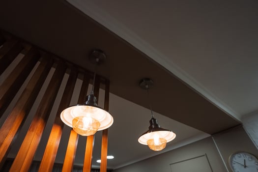 In a room adorned with wooden accents and features, two decorative lights elegantly hang from the ceiling, situated conveniently near a ticking clock that adds to the ambiance photo