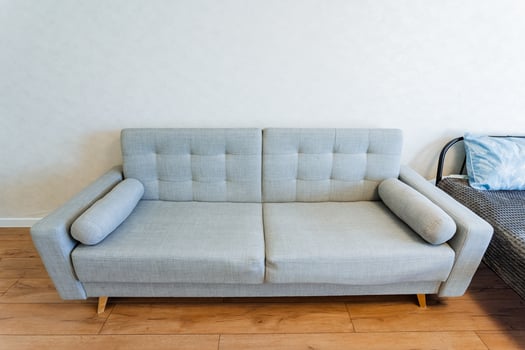 A grey couch is in a living room next to a bed, providing comfort and style photo