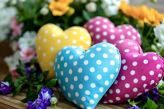 Colorful polka dot heart shaped pillows resting on wooden surface photo