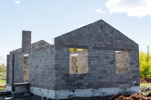Brick house rising in field against sky, surrounded by plants and grass photo