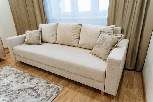 A cozy living room features a sleek white couch by a large window, filling the space with natural light, creating a warm atmosphere for relaxation and socializing with family or friends photo