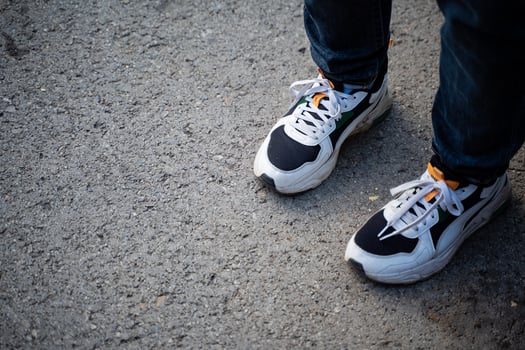 A person is currently wearing a stylish and fashionable pair of black and white sneakers that are perfect for casual outings or athletic activities, providing comfort and support photo