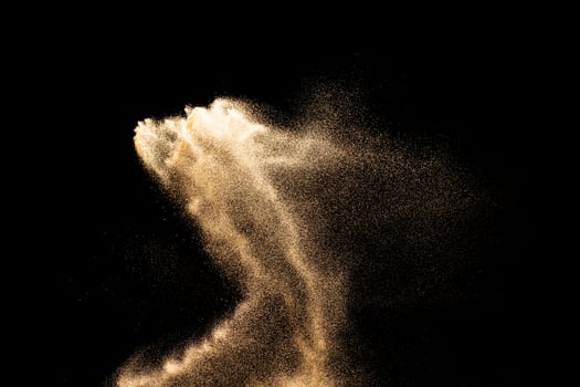 Sand flying explosion isolated on black background. photo