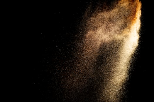 Sand flying explosion isolated on black background photo