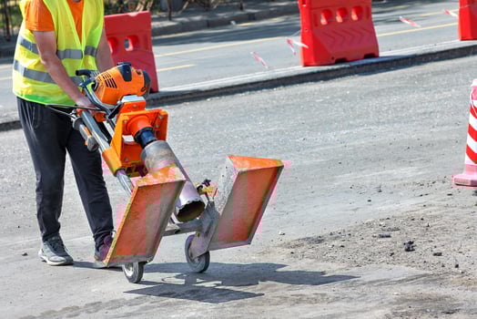 A road worker pulls a petrol drill to cut asphalt concrete samples. photo