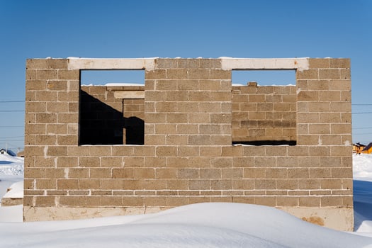 A brick house is being constructed against a snowy landscape photo