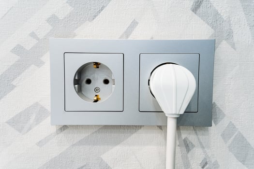 A white plug is plugged into an outlet photo