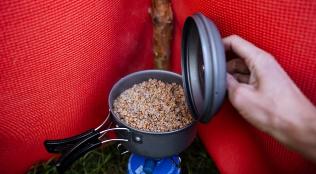 A person is opening a pot with food in it photo