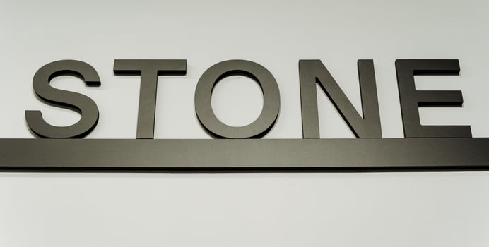 A stylish rectangular stone sign with automotive exterior details, metal, brand logo, and signage graphics against a white background, perfect for an automotive setting photo