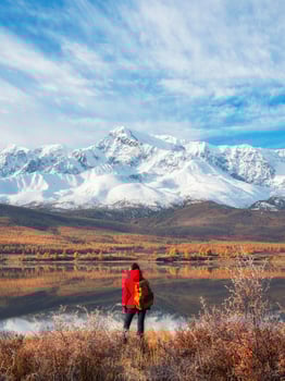 Back view of traveler in a red looking to mountain lake photo
