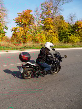 Woman biker on a black motorcycle in traffic on a rural autumn road. photo