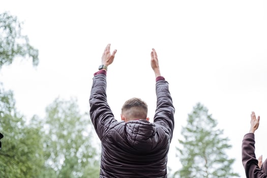 In a picturesque natural environment, a cheerful group of individuals energetically lift their hands with joy under the clear sky, showcasing genuine happiness and excitement photo
