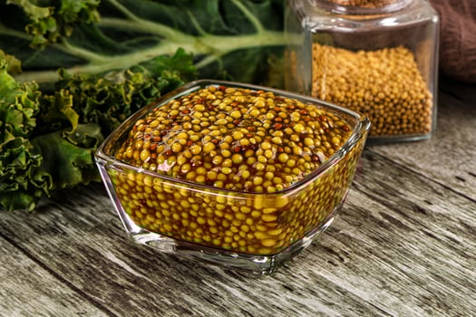 A bowl of mustard and a jar of mustard seeds photo