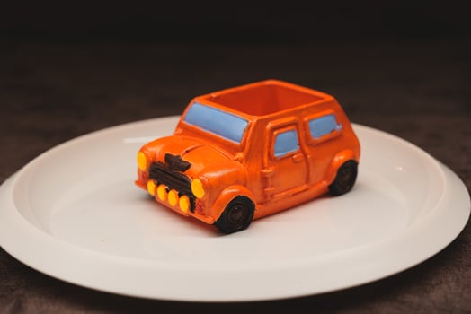 A brilliantly crafted and creative dessert shaped like an orange car displayed artfully on a plate photo