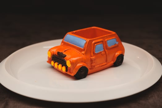 A creatively designed dessert shaped like a car, presented beautifully on a white plate photo