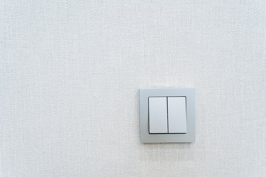 Rectangular white light switch on a white wall with symmetrical placement photo