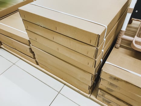 There is a stack of cardboard boxes that are positioned neatly on top of one another resting on a shelf. These boxes are organized and are made of durable cardboard material photo