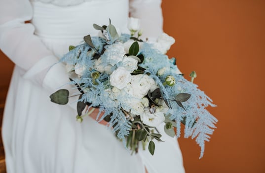 A bride holding a blue and white bouquet photo