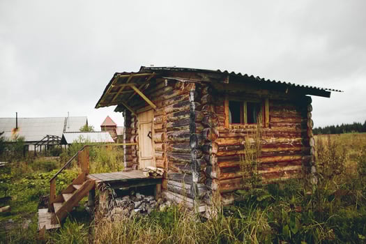 An old wooden cabin in the middle of a field photo