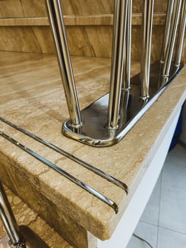 This image features a detailed closeup view of a sturdy metal railing positioned alongside a beautifully crafted wooden staircase, showcasing the contrast between materials photo