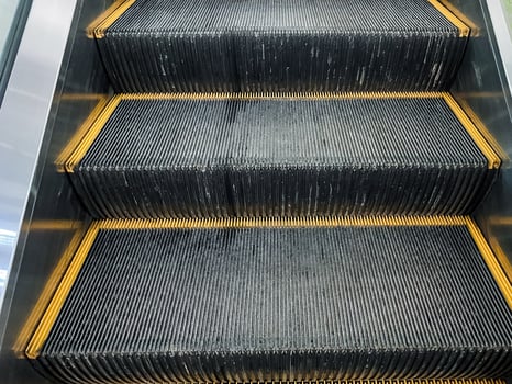 Closeup of a symmetrical escalator with yellow striped steps made of composite material photo
