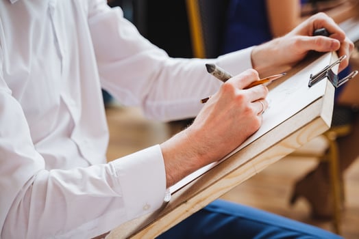Man using pencil to draw gesture on paper during formal event photo