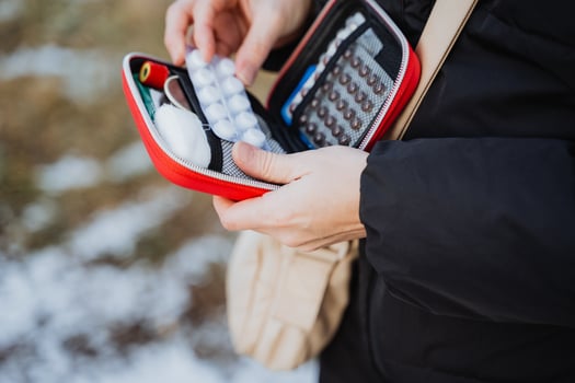 A person is taking pills out of a red case photo