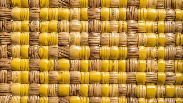 Closeup of Woven Straw and Yellow Plastic Patterned Basket Surface Texture Background photo