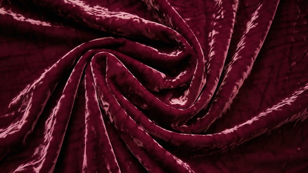 Soft Burgundy Velvet Fabric with Elegant Folded Swirls in Luxurious Textured Background photo