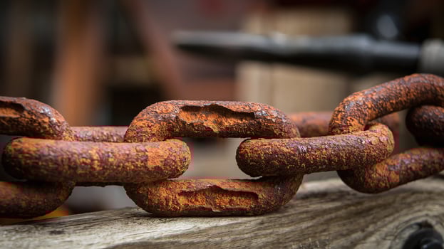Closeup of Rusted Iron Chain Links on Weathered Wood with Blurred Industrial Background photo