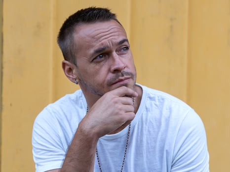 Pensive Man with Short Hair Wearing a White Shirt Against Yellow Background Represents Contemplation photo