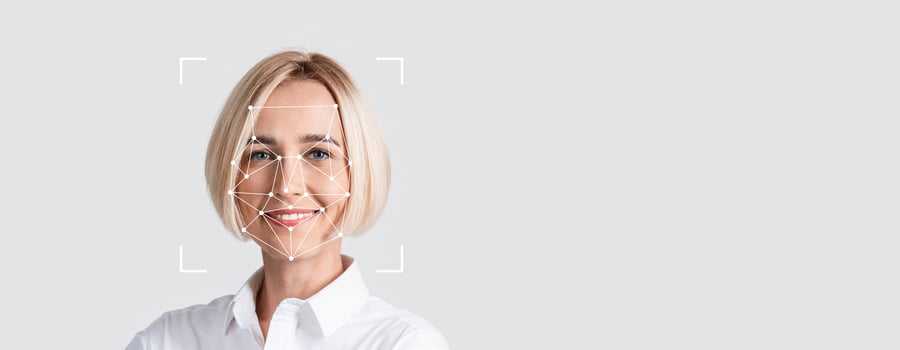A person is engaged in facial recognition technology, smiling toward the camera against a blank background. The focus is on their facial features, illustrating identification processes. photo