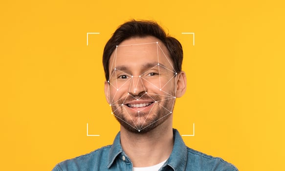 An individual stands against a bright yellow background, showcasing facial recognition technology. Geometric lines outline his facial features, emphasizing identity and technology. photo