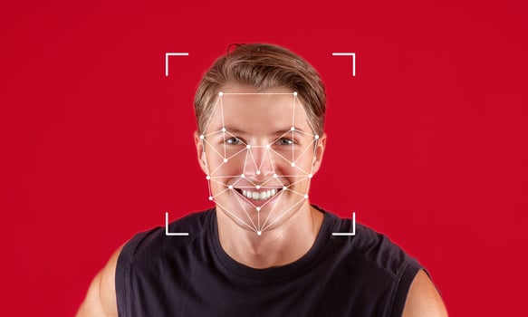 A man with a joyful expression is captured in front of a red background. Facial recognition software marks key points on his face, demonstrating advanced identification technology. photo