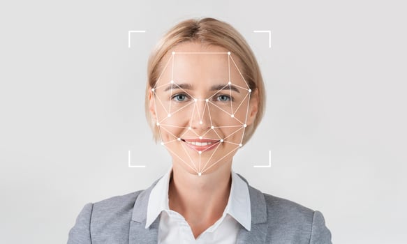 A professional woman smiles while facial recognition technology analyzes her features. She stands against a plain background, highlighting the tech's identification capabilities. photo