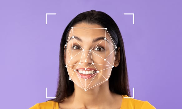 A woman with a bright smile illustrates facial identification technology against a plain purple background. The technology highlights her facial features, showcasing its capabilities. photo