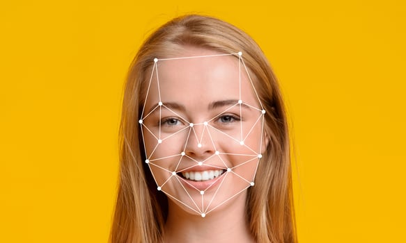 A young woman with long hair smiles confidently against a vibrant yellow background. Her face is overlaid with digital points, demonstrating facial recognition technology. photo