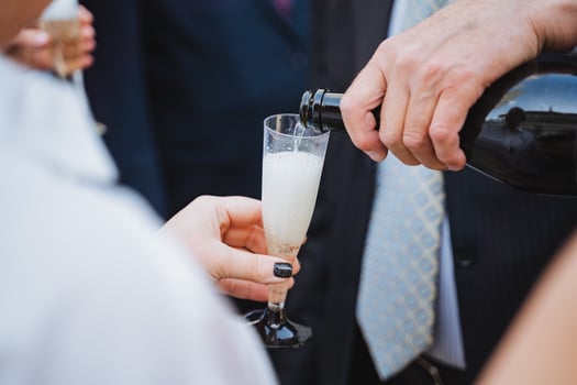 Man in formal wear pours champagne as woman holds glass at event photo