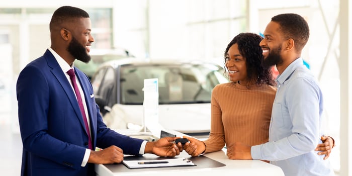 Purchasing Car. Happy Black Couple Taking Key From Manager In Dealership Center After Buying New Automobile, Young African American Spouses Choosing Auto In Modern Showroom, Smiling To Salesperson photo